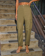 Olive green high-waist cargo pants with side pockets, elastic waistband, tapered jogger ankles, styled with strappy heels